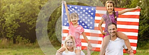 happy family with the flag of america USA at sunset outdoors