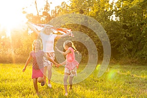 happy family with the flag of america USA at sunset outdoors