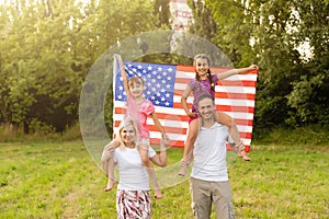 happy family with the flag of america USA at sunset outdoors