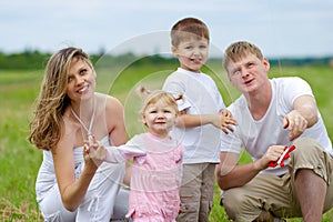 Happy family fly a kite together in summer field