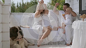 Happy family of four with children and a dog having fun showing hand gestures. Warm family relationships