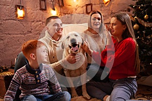 A happy family of four and a dog celebrate the New Year. Dad, mom, son and daughter love the dog and have fun against the