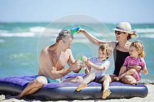 Happy family of four having fun on the beach