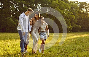 Happy family of four with kids walking in summer park enjoying beautiful nature.