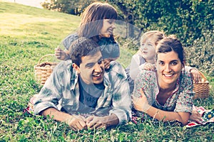 Happy family of four lying in the grass in autumn