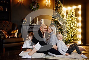 Happy family of four persons near decorated christmas tree