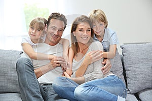 Happy family of four relaxing on sofa