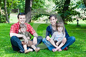 Happy family of four sitting on grass