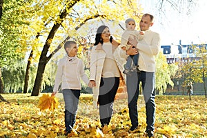 A happy family of four spend time in the autumn park. Family walking in the park and enjoying a sunny day