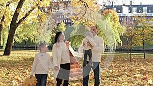 A happy family of four spend time in the autumn park. Family walking in the park and enjoying a sunny day