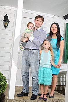 Happy family of four stand on porch of new cottage.