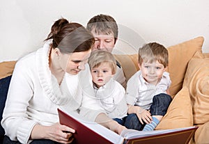 Happy family of a four watching old photos at home.