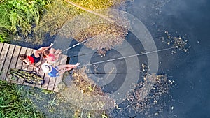 Happy family and friends fishing together outdoors near lake in summer, aerial top view