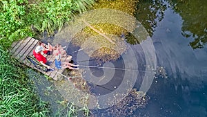 Happy family and friends fishing together outdoors near lake in summer, aerial top view