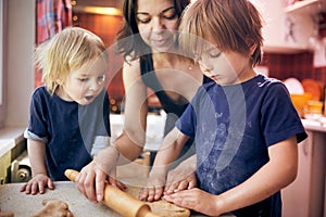 Happy family funny boys and their mom are preparing the dough, bake cookies in the kitchen at home