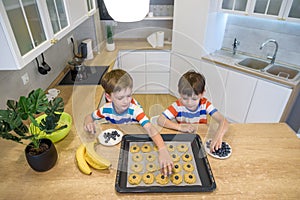 Happy family funny kids are preparing the dough, bake cookies in the kitchen. Put berry and blueberry in all biscuits