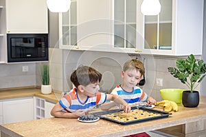 Happy family funny kids are preparing the dough, bake cookies in the kitchen. Put berry and blueberry in all biscuits