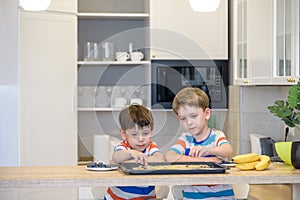 Happy family funny kids are preparing the dough, bake cookies in the kitchen. Put berry and blueberry in all biscuits