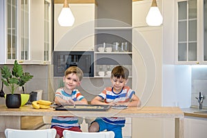 Happy family funny kids are preparing the dough, bake cookies in the kitchen. Put berry and blueberry in all biscuits