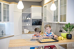 Happy family funny kids are preparing the dough, bake cookies in the kitchen. Put berry and blueberry in all biscuits