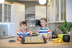 Happy family funny kids are preparing the dough, bake cookies in the kitchen. Put berry and blueberry in all biscuits