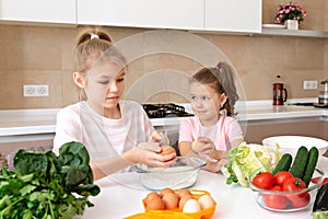 Happy family funny kids are preparing the dough, bake cookies in the kitchen. sisters having fun together laughing