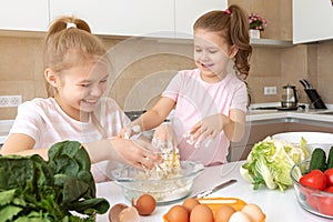 Happy family funny kids are preparing the dough, bake cookies in the kitchen. sisters having fun together laughing