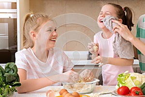Happy family funny kids are preparing the dough, bake cookies in the kitchen. sisters having fun together laughing