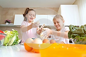 Happy family funny kids are preparing the dough, bake cookies in the kitchen. sisters having fun together laughing