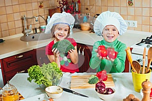 Happy family funny kids are preparing the a fresh vegetable salad in the kitchen