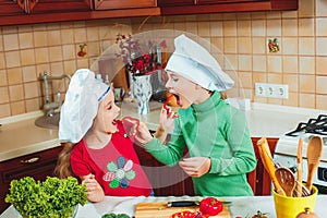 Happy family funny kids are preparing the a fresh vegetable salad in the kitchen