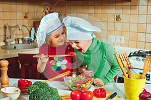 Happy family funny kids are preparing the a fresh vegetable salad in the kitchen