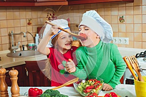 Happy family funny kids are preparing the a fresh vegetable salad in the kitchen