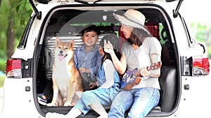 Happy family getting ready for road trip on a holiday. Happy asian children and Mother with shiba inu sitting and Sing Song in car