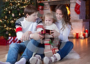 Happy family with gifts sitting at Christmas tree