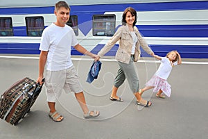 Happy family with girl going on railway station