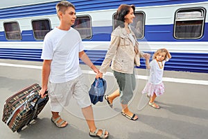 Happy family with girl going on railway station