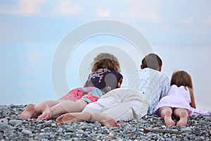 Happy family with girl lying on beach, lying back
