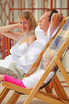 Happy family with girl reclining on chaise lounges