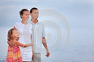 Happy family with girl standing on beach, evening