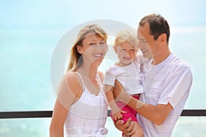 Happy family with girl on veranda near seacoast