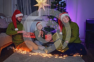 Happy family gives gifts at the Christmas tree in night light of the garla