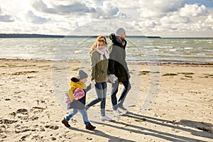 Happy family going to picnic on beach in autumn