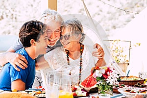 Happy family with grandfathers and grandson together hugging and smilng with joy - people have fun and love - lunch together at photo