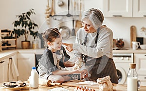 Happy family grandmother and granddaughter child cook in the kitchen, knead dough, bake cookies