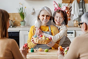 Happy family grandmother and little granddaughter holding wicker basket full of painted boiled eggs