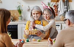 Happy family grandmother and little granddaughter holding wicker basket full of painted boiled eggs