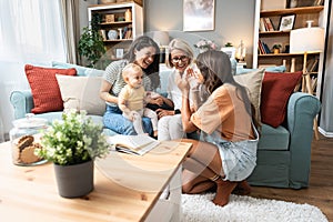 Happy family. Grandmother, mother, aunt and little baby having fun at home. Relatives visiting new born child