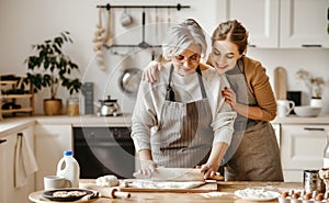 Happy family grandmother  old mother mother-in-law and daughter-in-law daughter cook in kitchen, knead dough, bake cookies