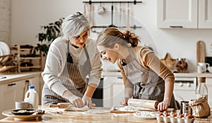 Happy family grandmother  old mother mother-in-law and daughter-in-law daughter cook in kitchen, knead dough, bake cookies